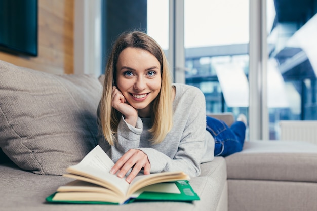  woman reads an interesting book while lying on the couch resting after work