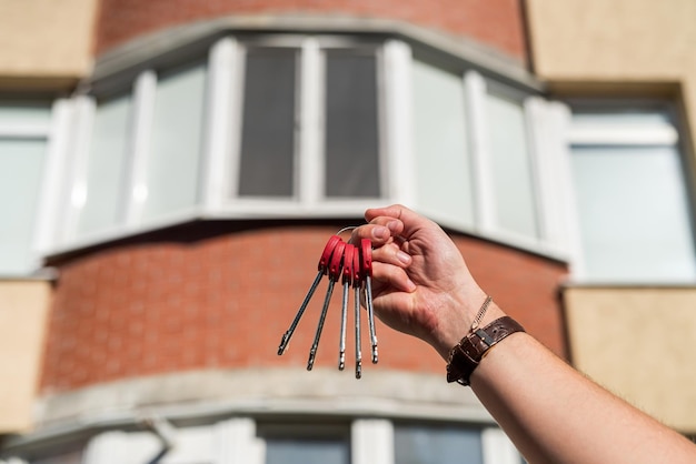 Woman real estate agent hands over the keys to new house against the background of building