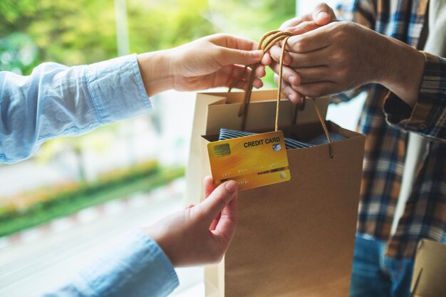 Foto una donna riceve borse della spesa dal fattorino e usa una carta di credito per il pagamento