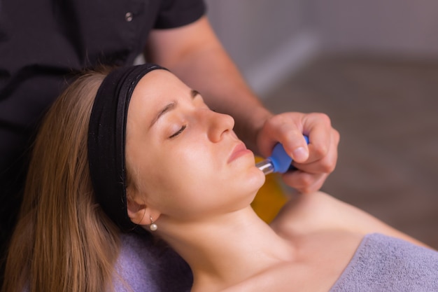 Woman receives facial cupping massage facial rejuvenation at acupuncture wellness spa.