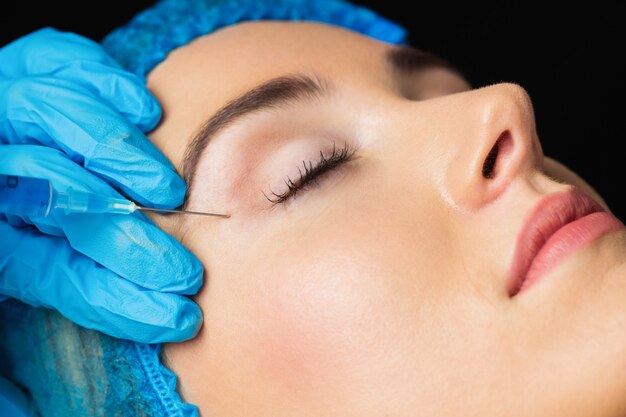 Woman receiving botox injection on her forehead