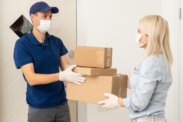 woman receiving boxes from postman at the door in home delivery concept. Woman received the parcel from the postman at home. Postman giving cardboard box to young woman.