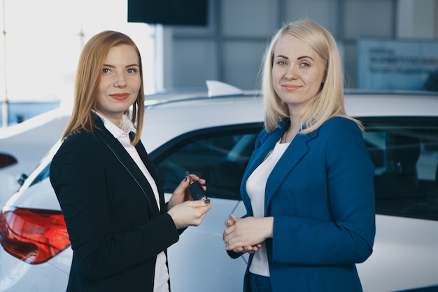 Woman receiving car keys from a dealer