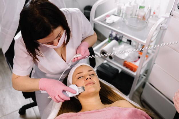 Woman receiving cleansing therapy with a professional
ultrasonic equipment in cosmetology office