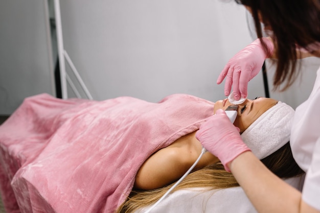 Donna che riceve la terapia di pulizia con un'apparecchiatura ad ultrasuoni professionale in ufficio di cosmetologia