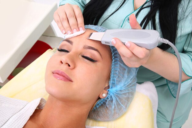 Woman receiving cleansing therapy with a professional ultrasonic equipment in cosmetology office