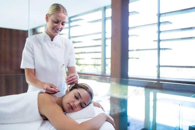 Woman receiving ear candle treatment