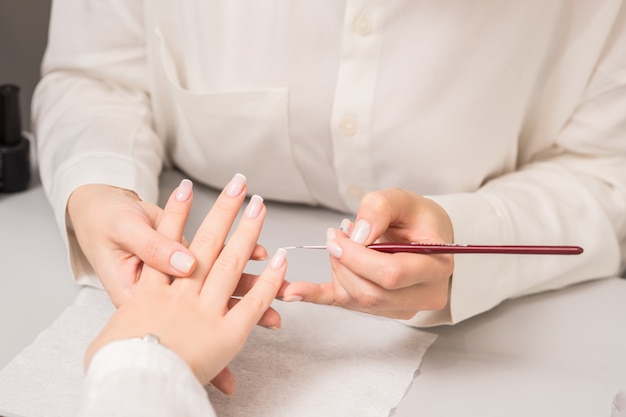 Woman receiving french manicure by beautician