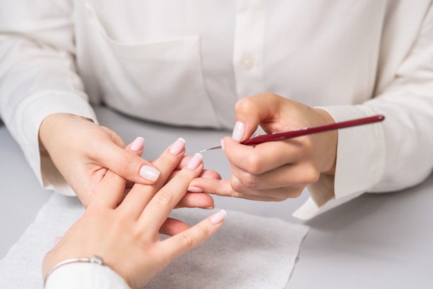 Woman receiving french manicure by beautician