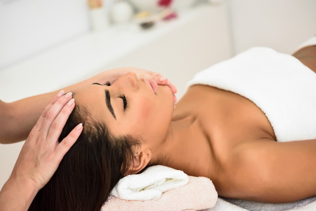 Woman receiving head massage in spa wellness center.