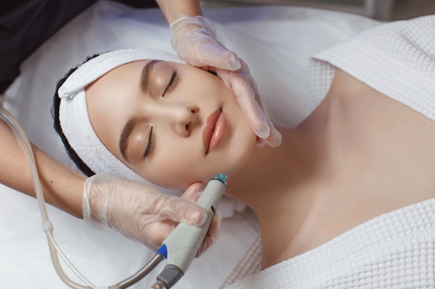 Photo woman receiving microdermabrasion therapy on forehead at beauty spa