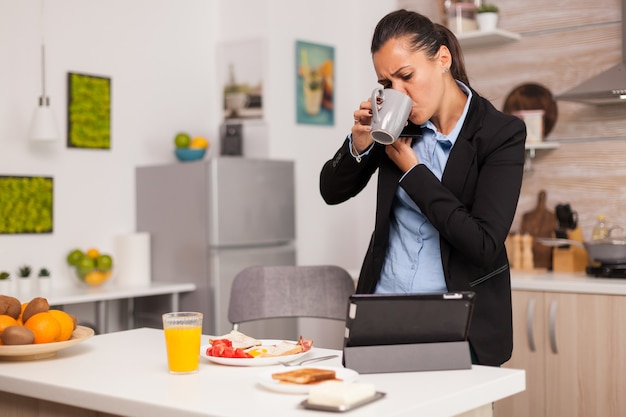 Woman receiving a new task on email in the morning while drinking her coffee