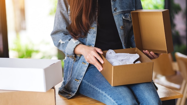 A woman receiving and opening a postal parcel box at home for delivery and online shopping concept