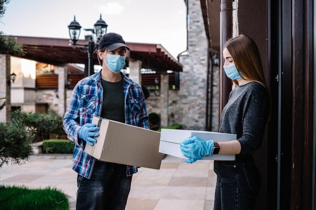 Woman receiving parcel from delivery man at the door medical mask quarantine