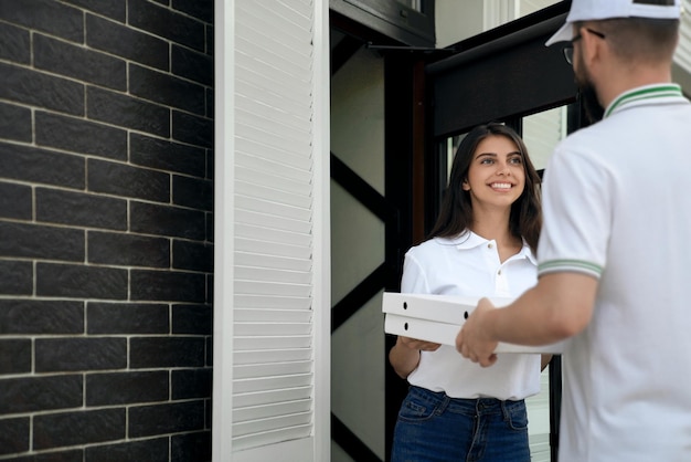 Woman receiving pizza from courier