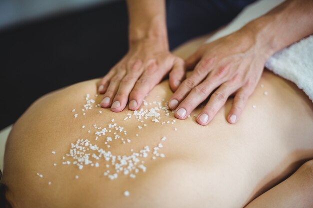 Woman receiving salt scrub therapy from physiotherapist