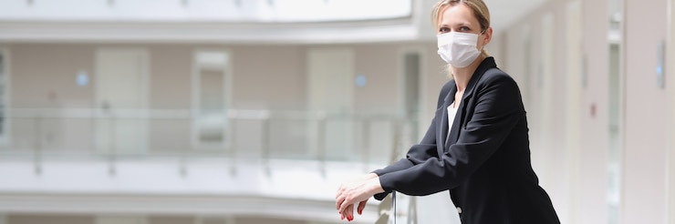 Photo woman receptionist in medical protective mask stands in corridor of hotel complex