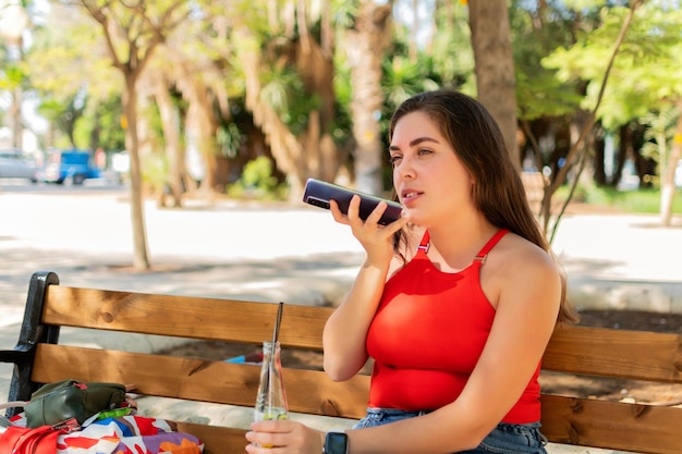 公園で電話で音声メッセージを録音する女性