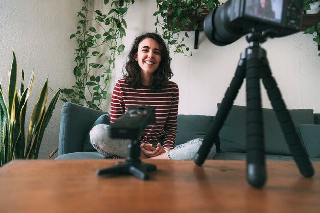 Woman recording herself at home for vlog laughing at camera Selective focus on girl Video blogging