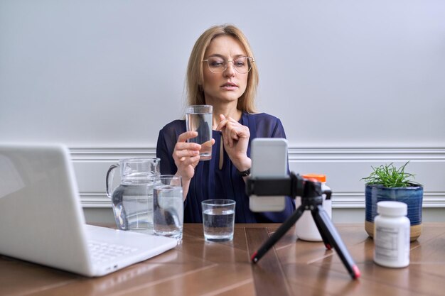 写真 水の健康的なライフスタイルの栄養についてのビデオを録画する女性