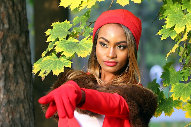 Donna in rosso su sfondo di foglie d'autunno