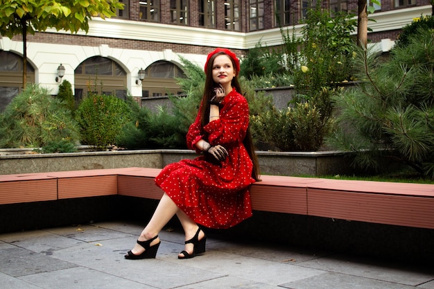 Foto una donna con un berretto rosso si siede su una panchina