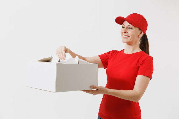 Woman in red cap, t-shirt giving food order cake box isolated on white background. Female courier holding dessert in unmarked cardboard box. Delivery service concept. Receiving package. Copy space.