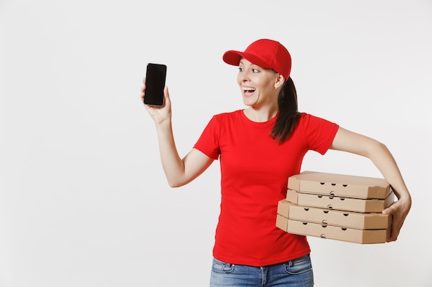 Woman in red cap, t-shirt giving food order italian pizza in cardboard flatbox boxes isolated on white background. Female courier holding mobile phone with blank black empty screen. Delivery concept.