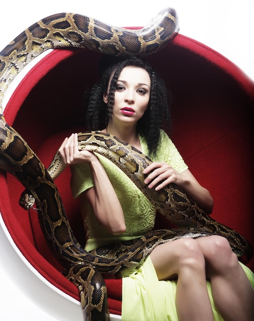 Photo woman in red chair holdung python