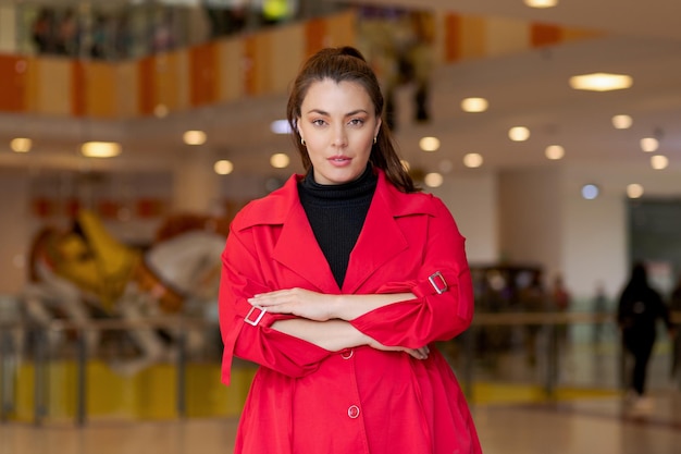 Photo woman in red coat poses with arms crossed and confident demeanor