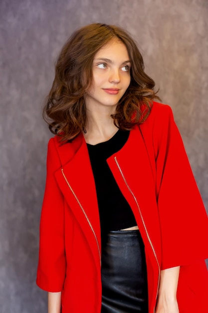 a woman in a red coat stands in front of a wall