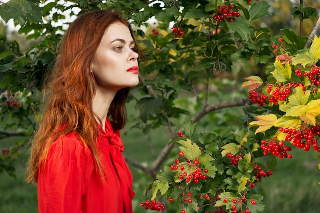 A woman in a red dress is not nature not a background of green leaves