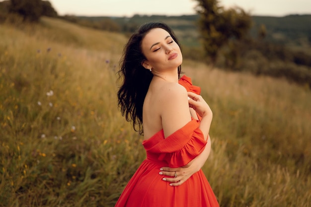 A woman in a red dress is standing in a field