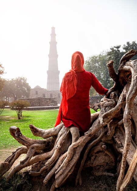 Woman in red dress looking at Qutub Minar