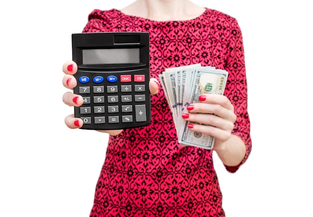 Женщина в красном платье, показывающая калькулятор и держащая деньги, изолирована на белом