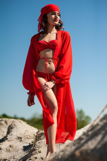 A woman in a red dress stands on the beach