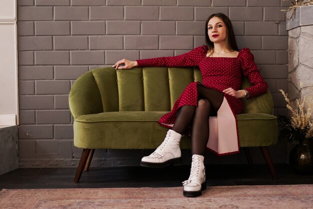 woman in a red dress and white shoes on a green sofa