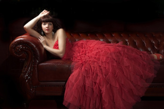 Woman in red evening dress lying on the sofa