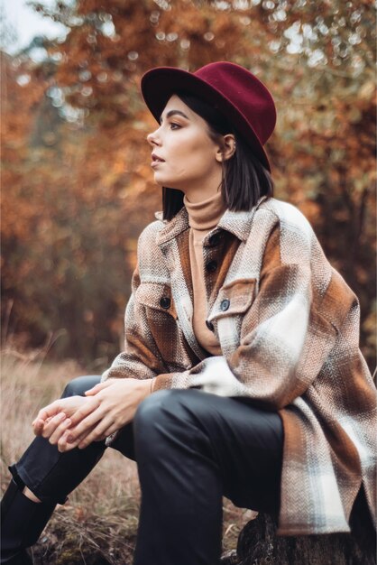 A woman in a red hat sits on a log in the woods