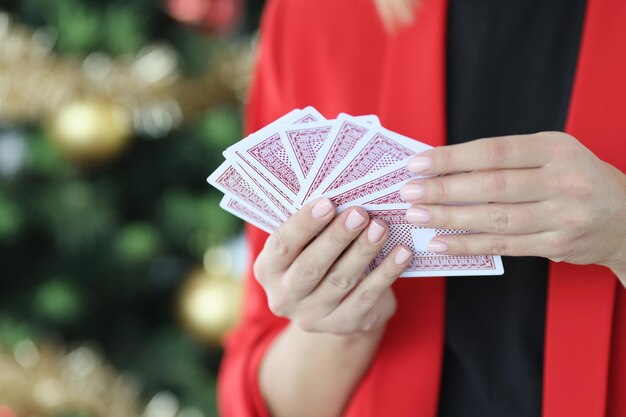 Woman in red jacket holds playing cards against background of new year tree christmas and