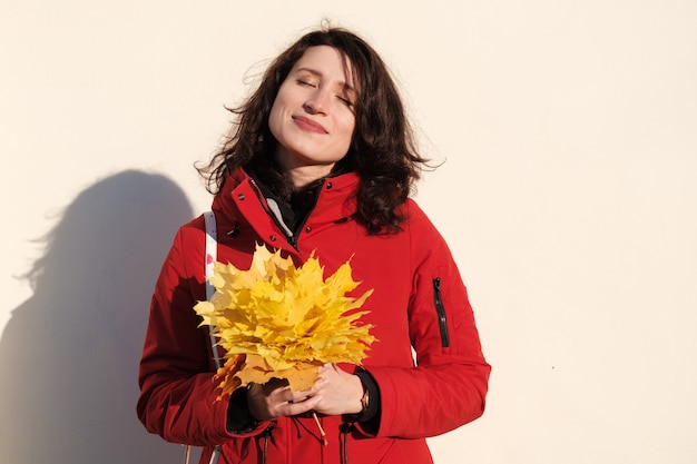 Woman in Red Jacket Holds Yellow Maple Leaves in Her Hands.