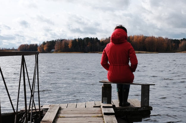 빨간 재킷을 입은 여성이 호수와 일몰을 바라보고 있습니다.