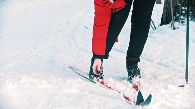 A woman in red jacket unsetting her boots from the ski