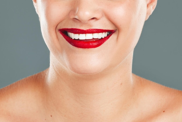 Woman red lipstick and smile for makeup cosmetics skincare or beauty against a grey studio background Happy female model smiling with cosmetic lips or mouth for beautiful color aesthetic treatment