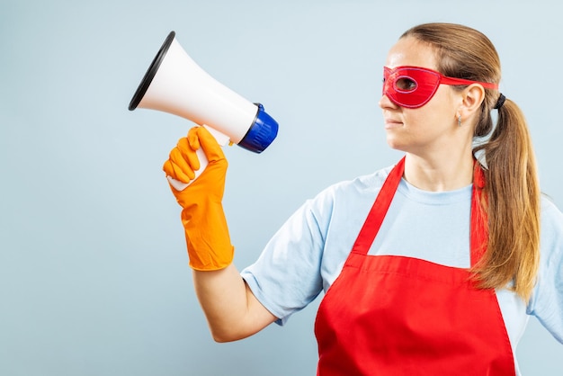 Photo woman in red mask gloves and apron with megaphone on blue background