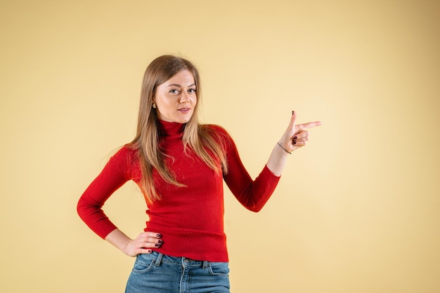 A woman in a red shirt points to the right on yellow background