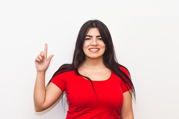 A woman in a red shirt points up at the index finger.