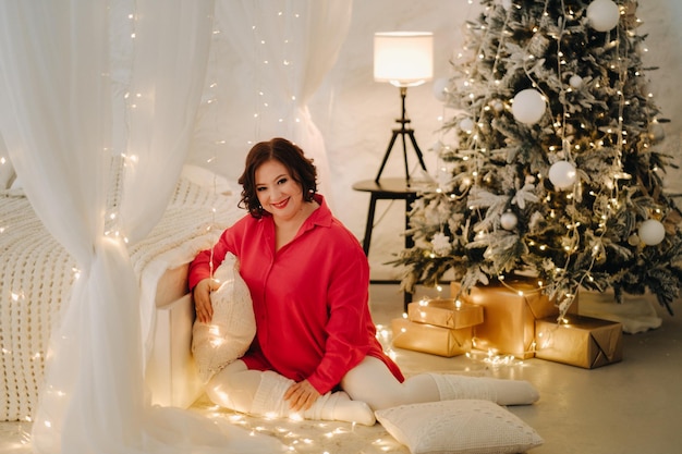 A woman in a red shirt in a room decorated for Christmas Home New Year's atmosphere