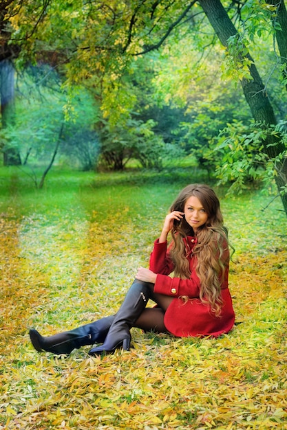 Woman in red sitting in autumn park.