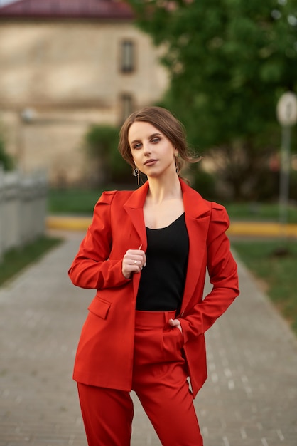 Woman in red suit posing on the street.